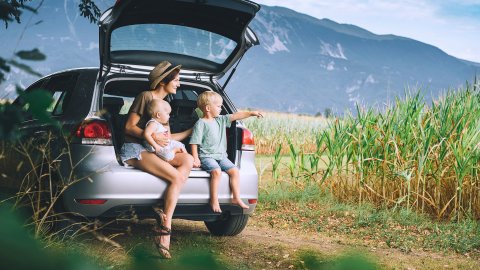 Mama met 2 kleine kinderen in de koffer van een gezinsauto